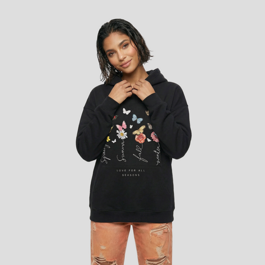 Person wearing a black hoodie with floral and butterfly designs on a white background