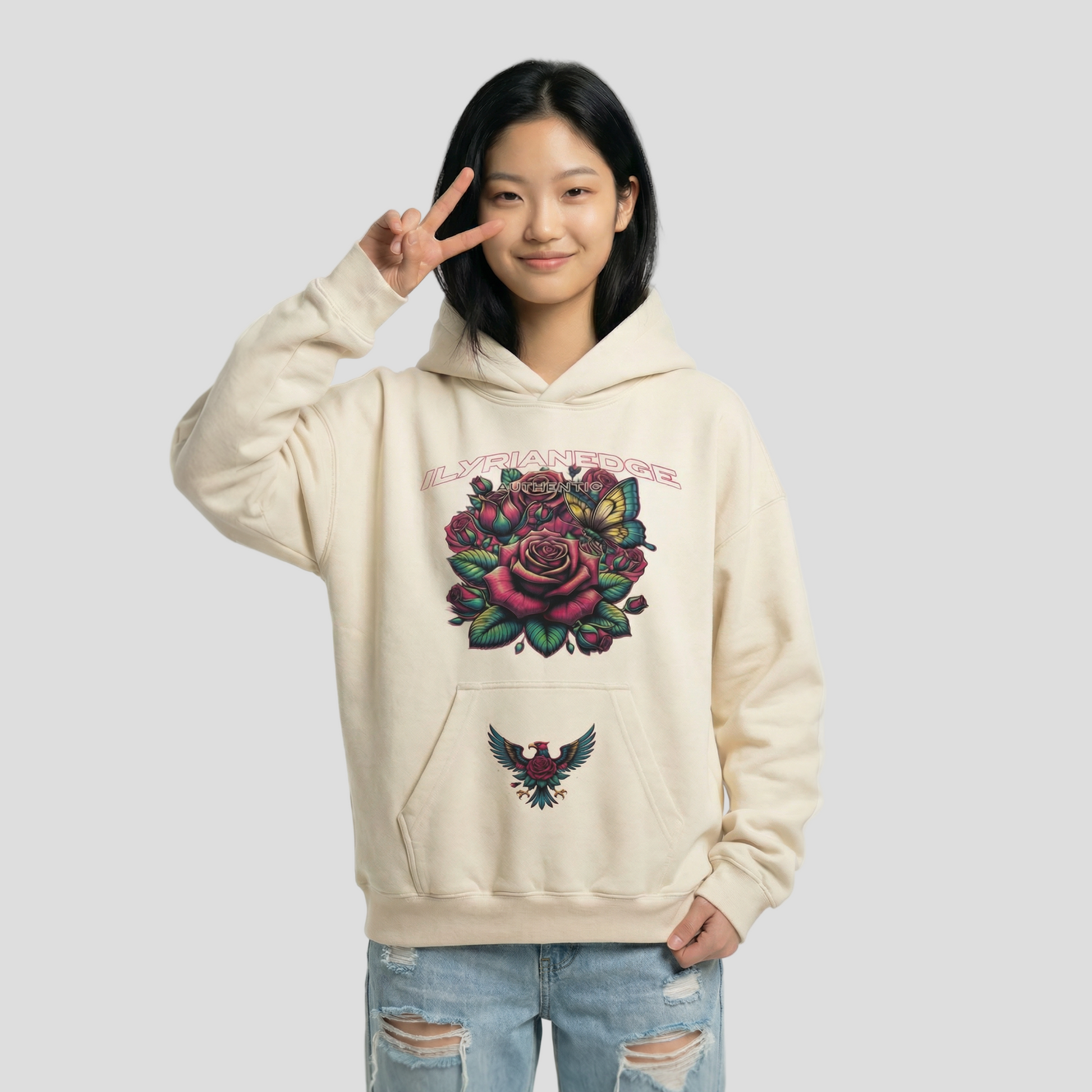 Person wearing a beige hoodie with floral and eagle design on a plain background