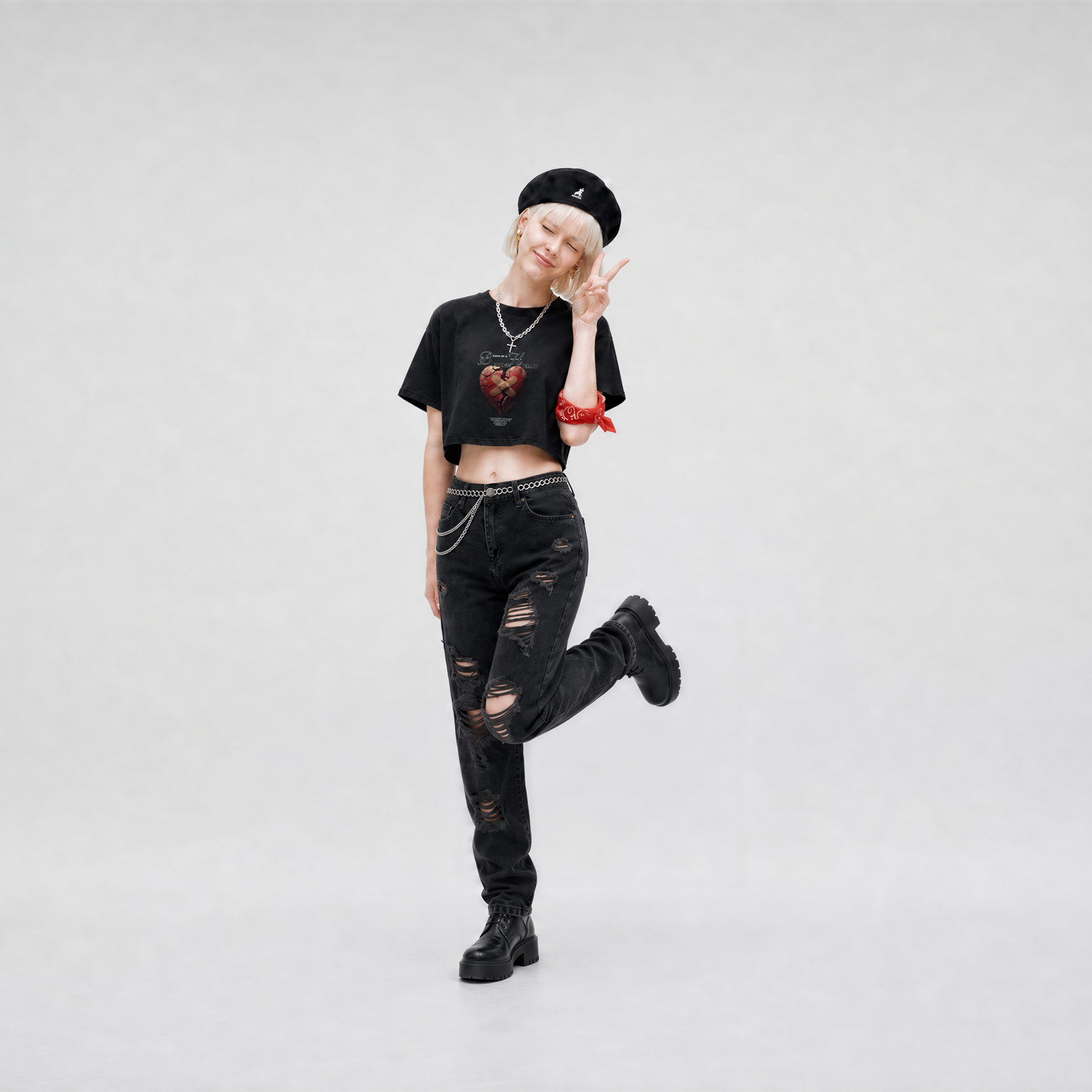 Person wearing a black outfit with a crop top, jeans, and boots on a white background