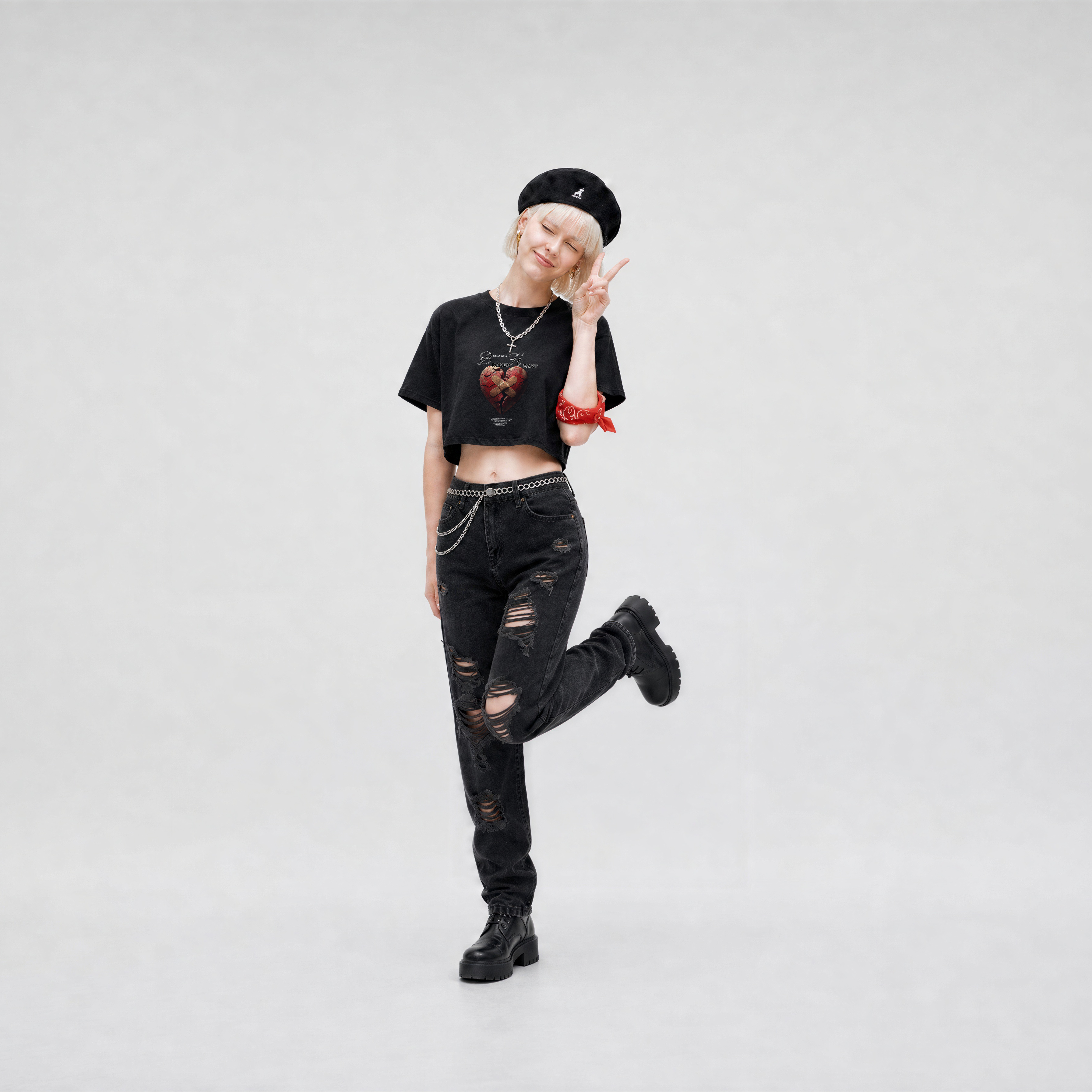 Person wearing a black outfit with a crop top, jeans, and boots on a white background
