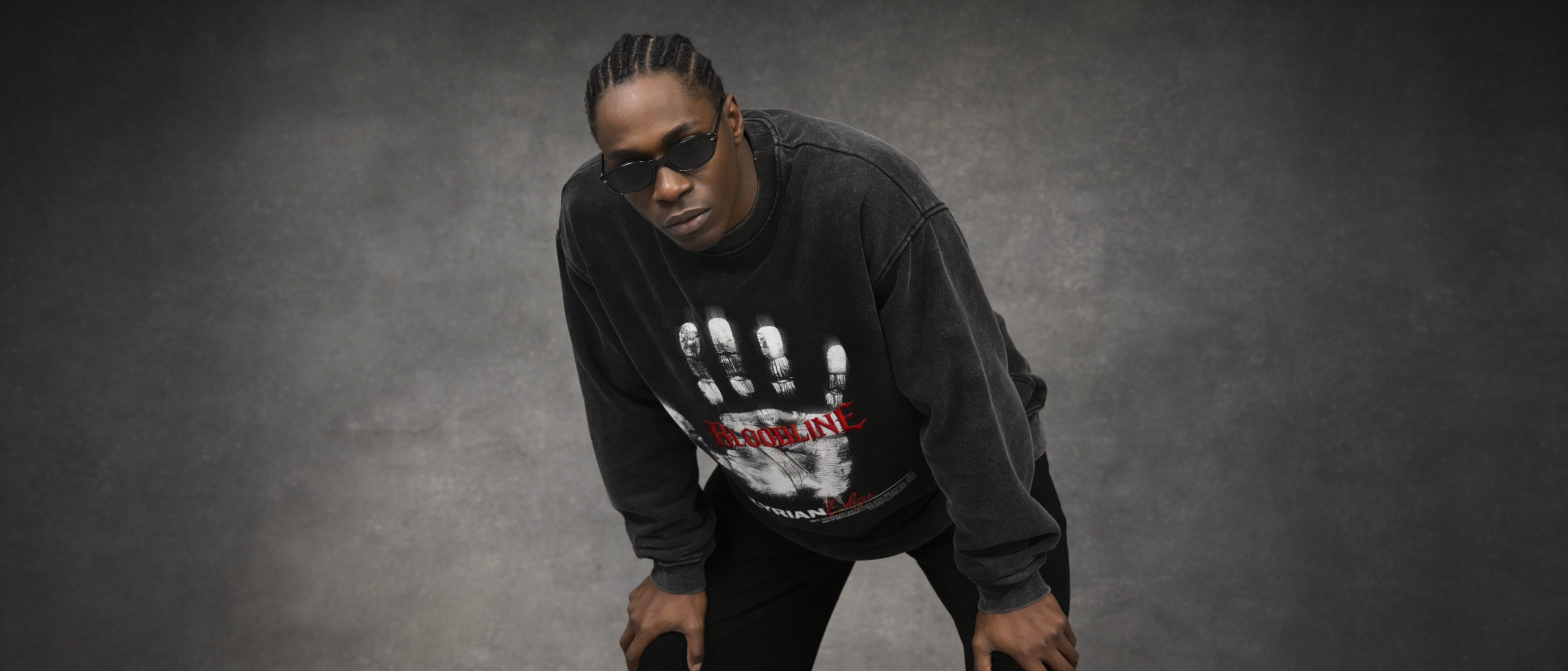 Person wearing a black sweatshirt with a graphic design on a gray background