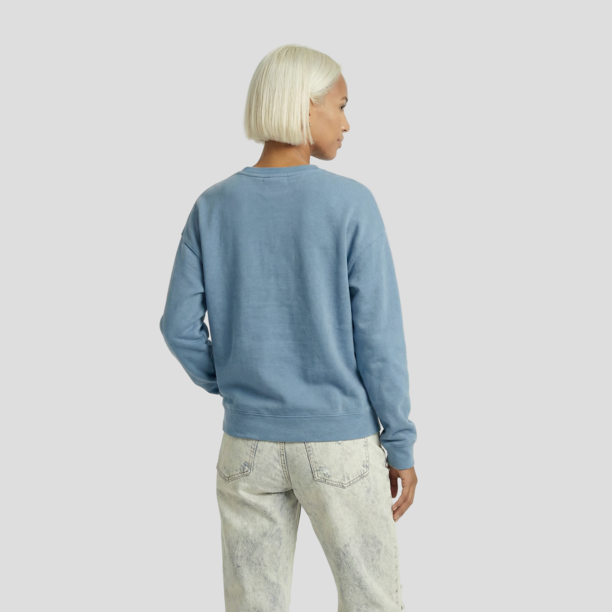 Person wearing a blue sweater and light-colored pants on a white background