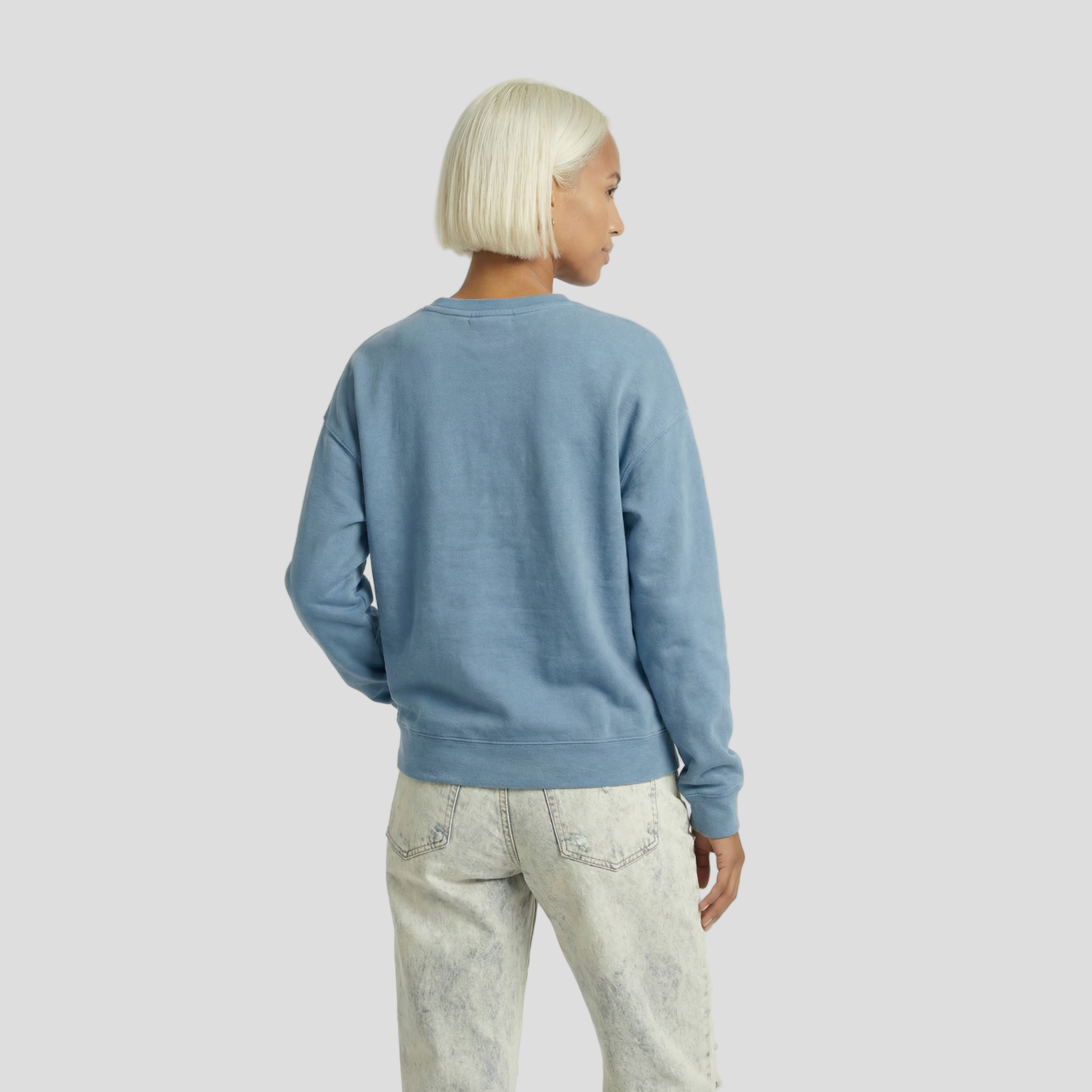 Person wearing a blue sweater and light-colored pants on a white background