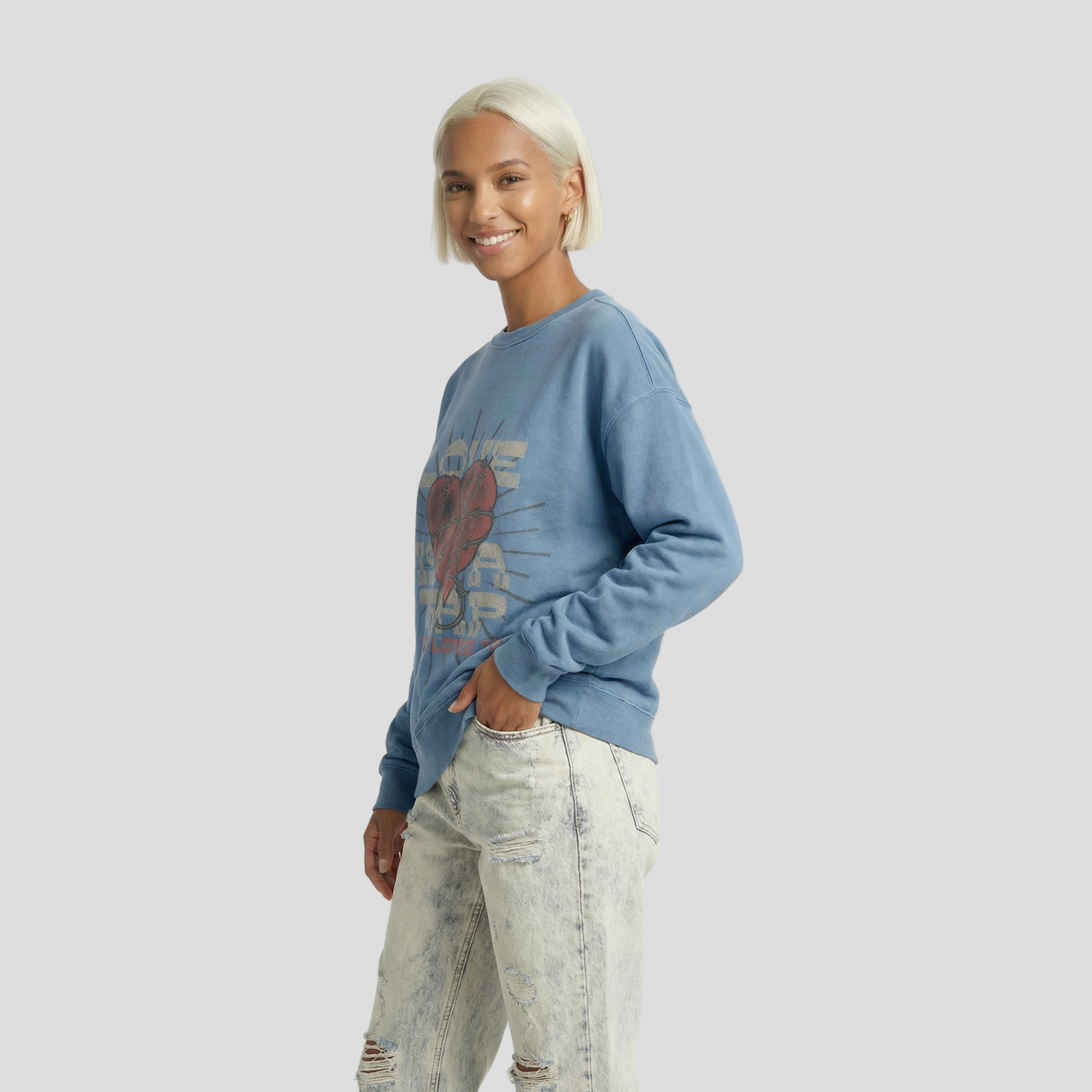Woman wearing a blue sweater with a graphic design and light jeans on a white background