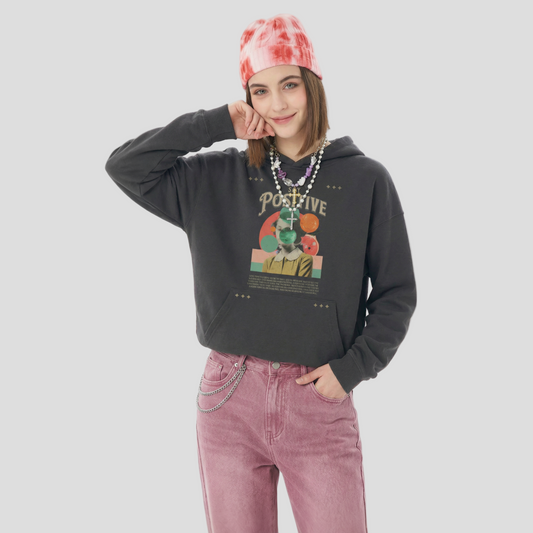 Person wearing a black hoodie with a colorful graphic and pink pants on a white background