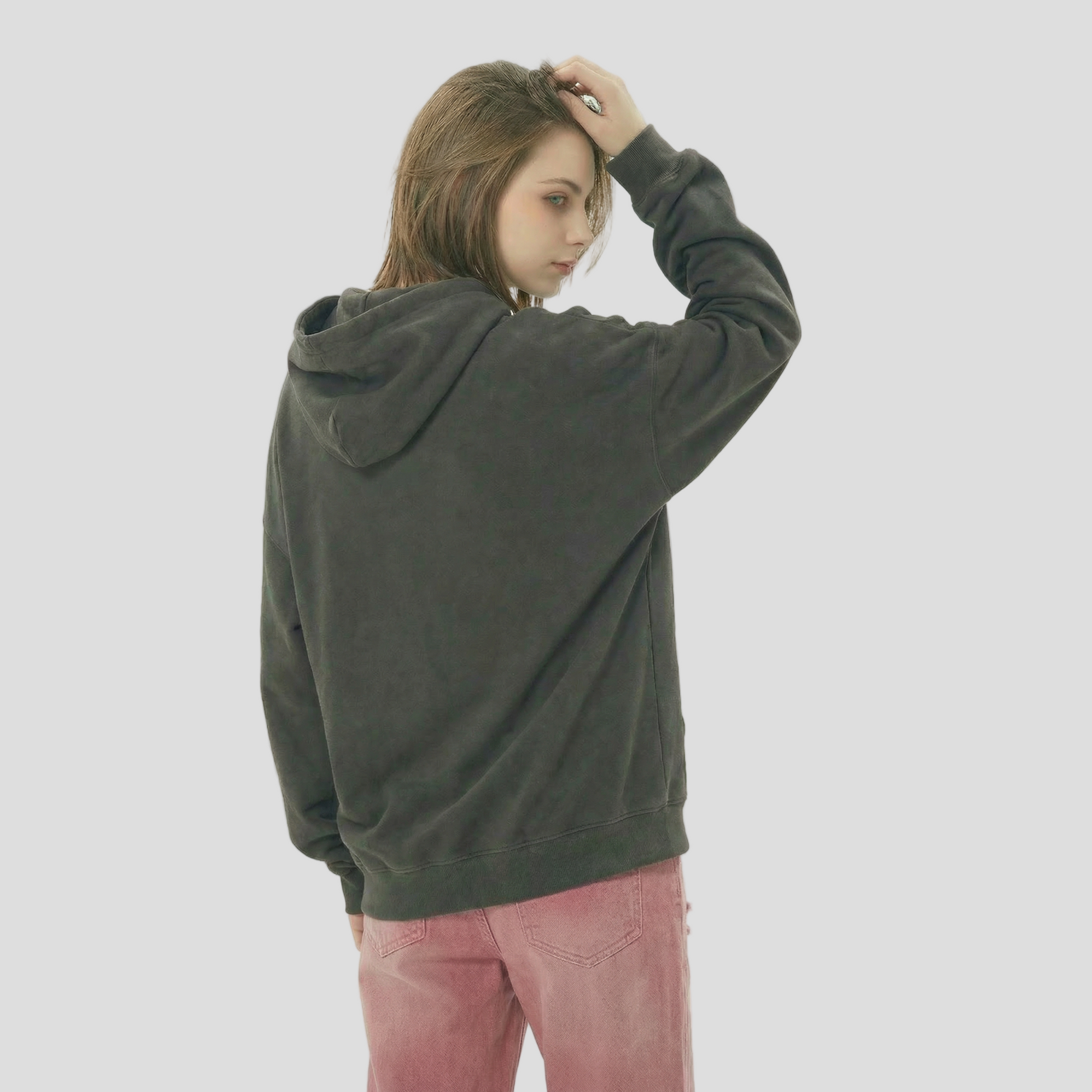 Person wearing a dark gray hoodie and pink pants on a light background