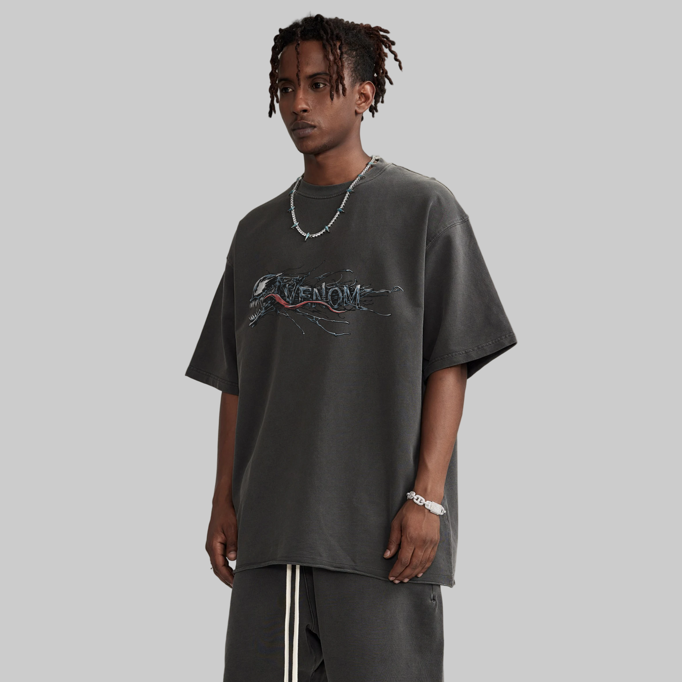 Person wearing a dark gray t-shirt with 'Venom' graphic design on a beige background