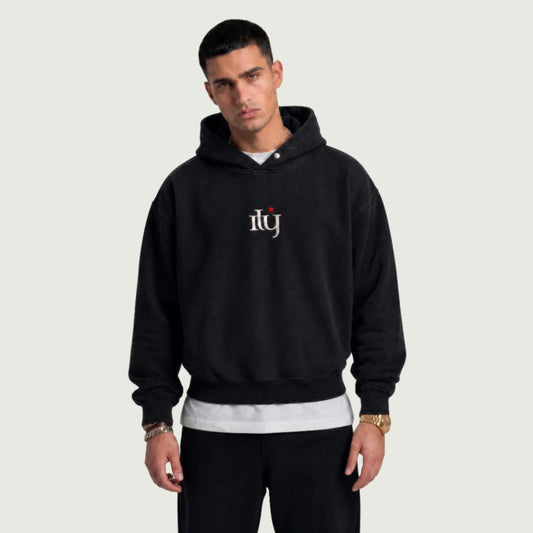 Man wearing a black hoodie with a logo on a gray background