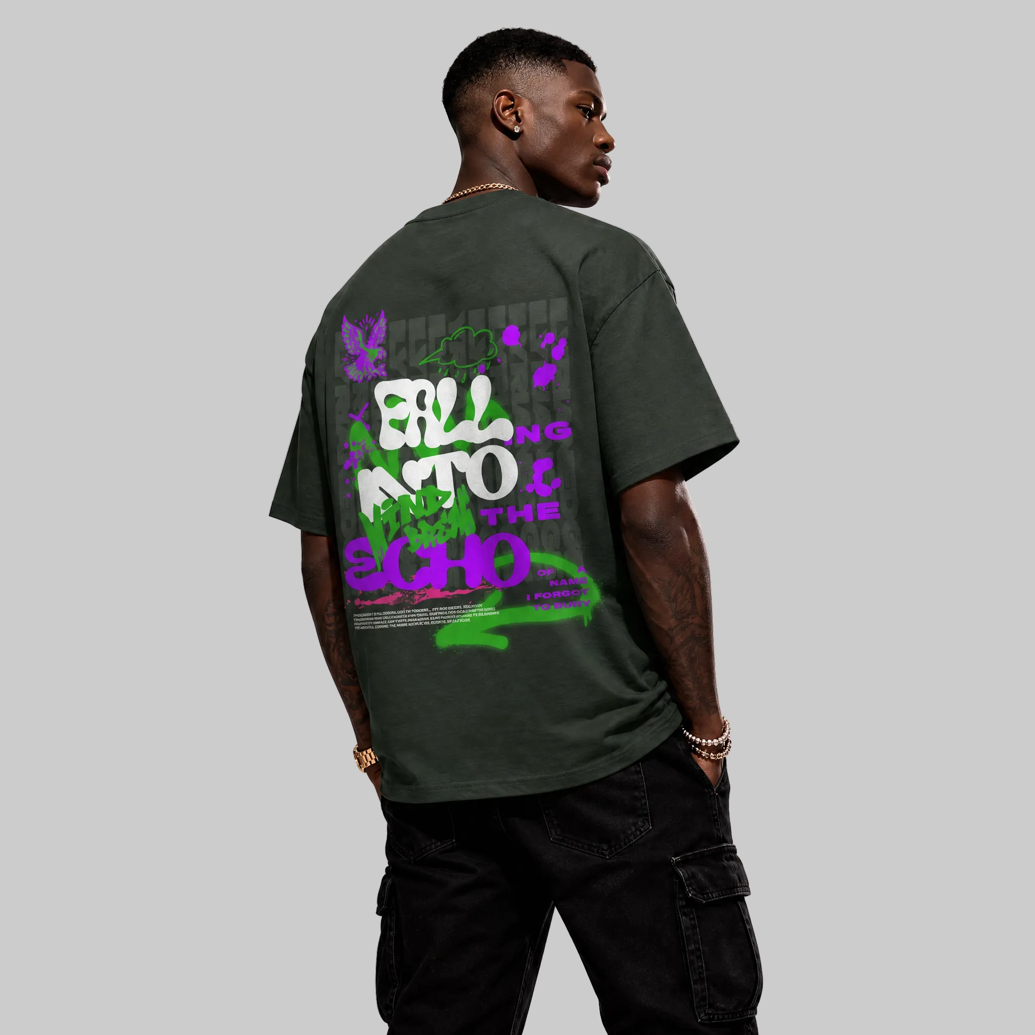 Person wearing a dark green t-shirt with colorful graphics on the back, standing against a white background.