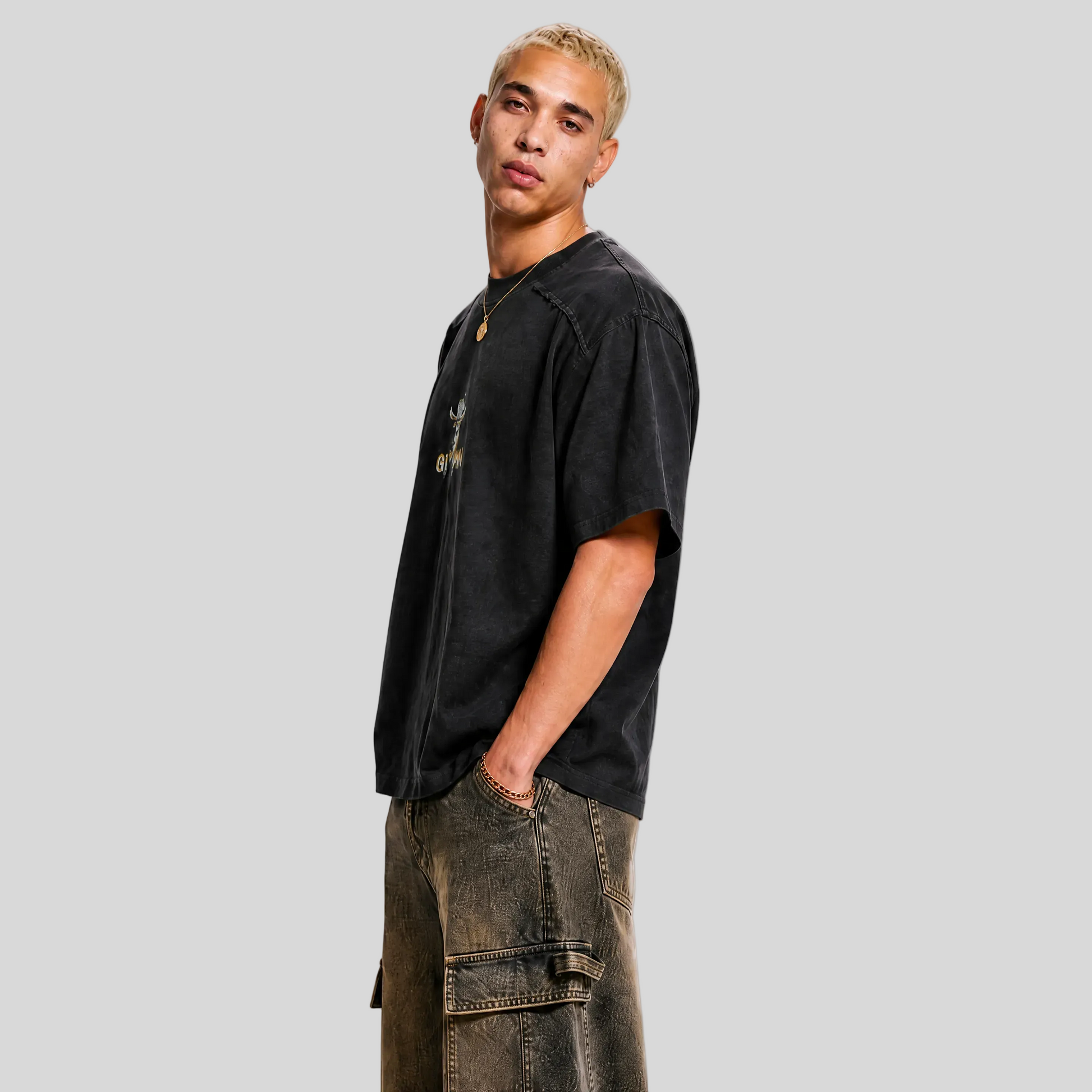 Man wearing a black t-shirt and brown cargo pants on a gray background