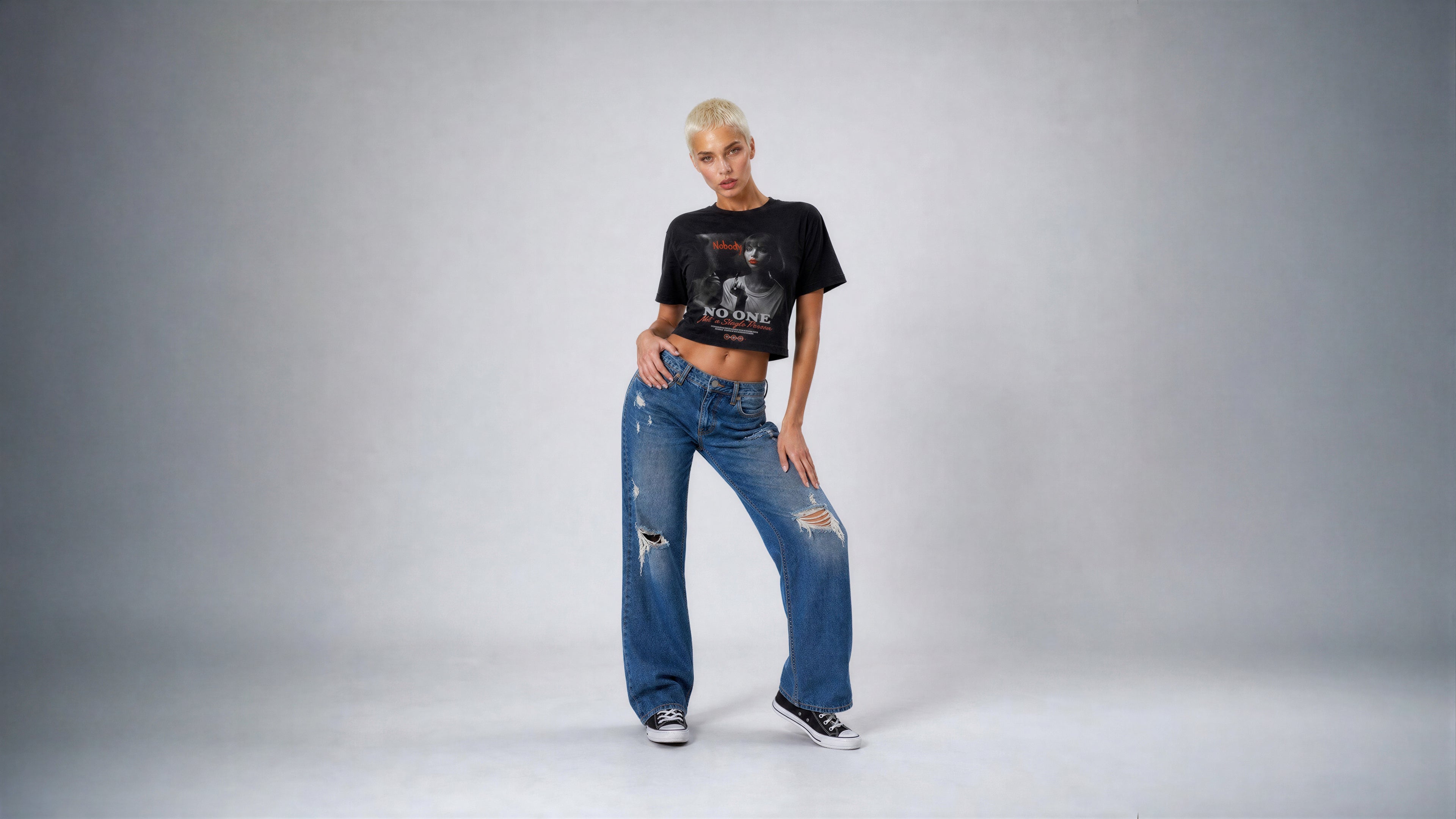 Person wearing a black t-shirt and blue jeans on a gray background